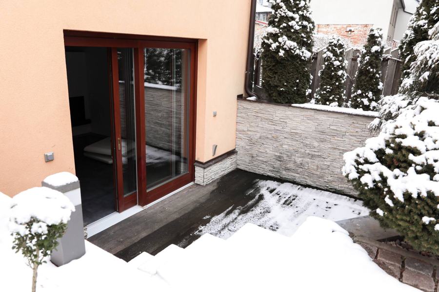 Prosklené dveře na terasu se zasněženými thujemi